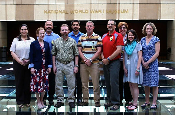 Modern photograph of a small group of adults posing for a picture on the glass bridge of the Museum.