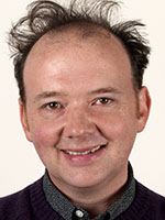 Headshot of a white man with messy dark brown hair