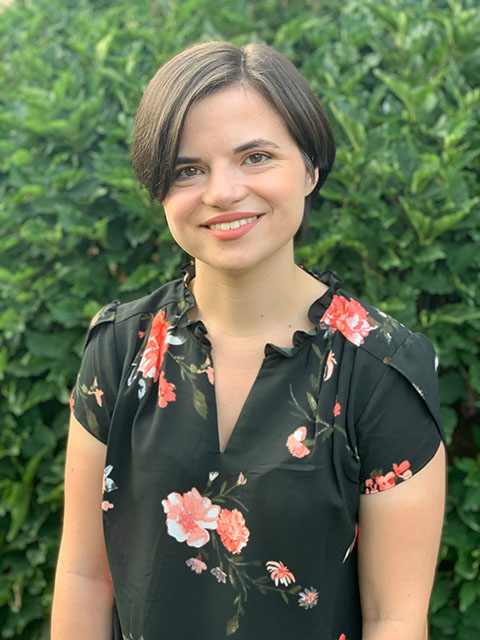 A young white woman with short brown hair in a black shirt with flowers on it