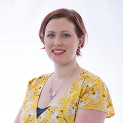 Headshot of a white woman with short auburn hair wearing a yellow flowered shirt