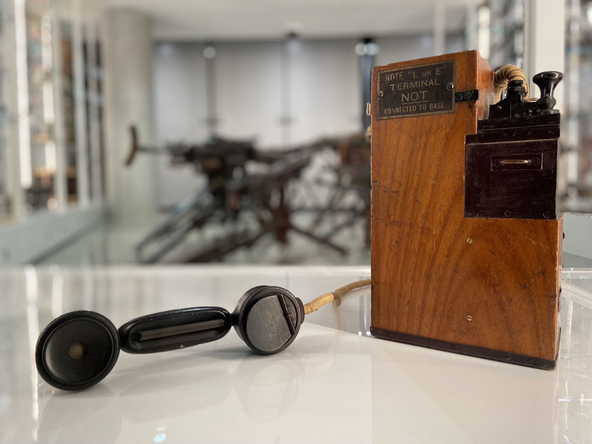 Modern photograph of a wooden box with metal switches and other mechanisms sticking out of it, including a telephone handset.