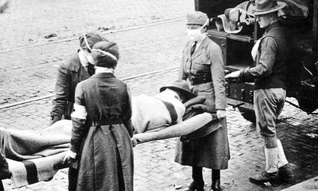 Black and white photograph of masked Red Cross orderlies carrying a stretcher with a prone person on it to an automobile with the Red Cross logo on it.