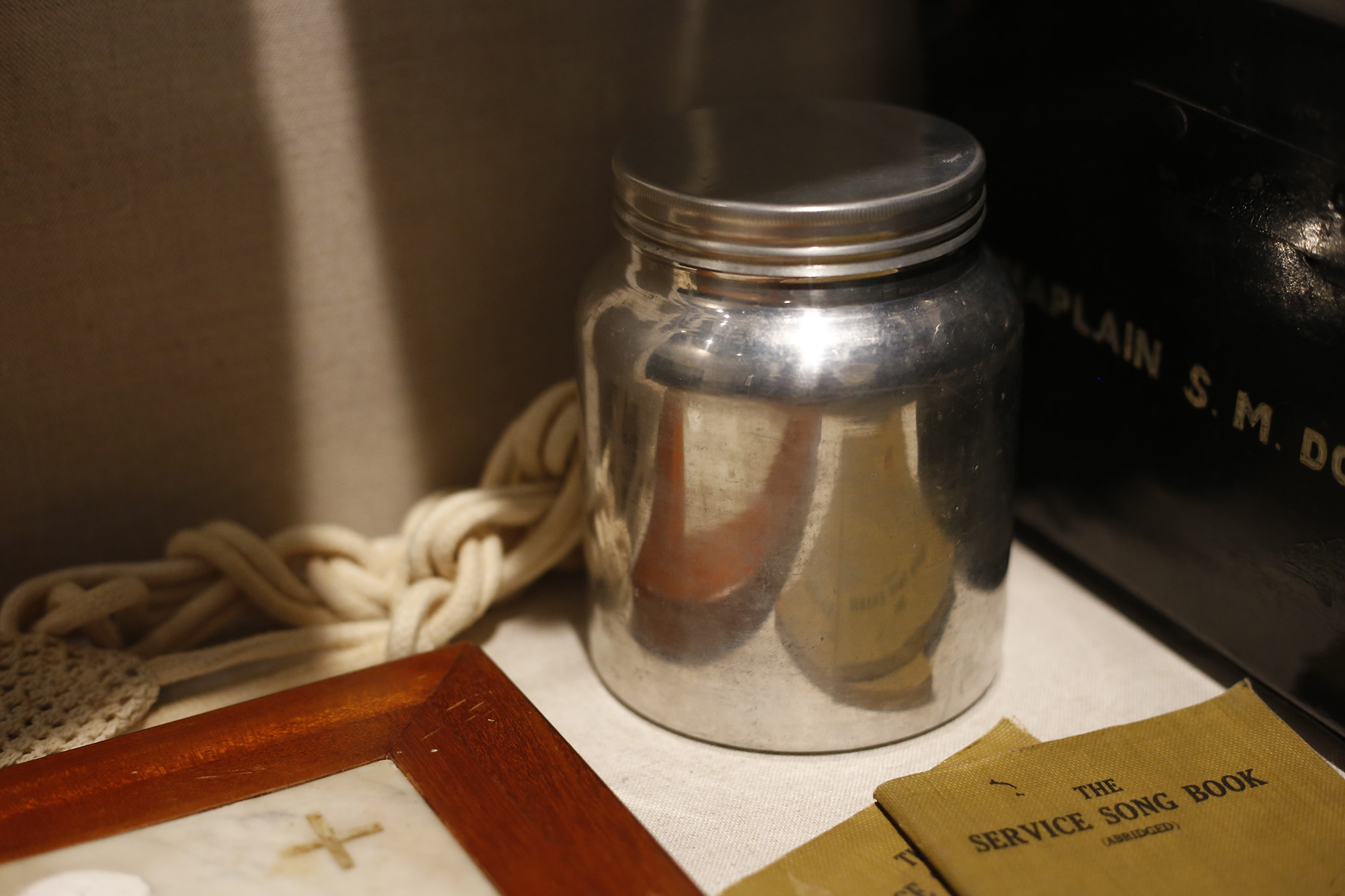 Modern photograph of a round silver lidded jar in a museum exhibit case.