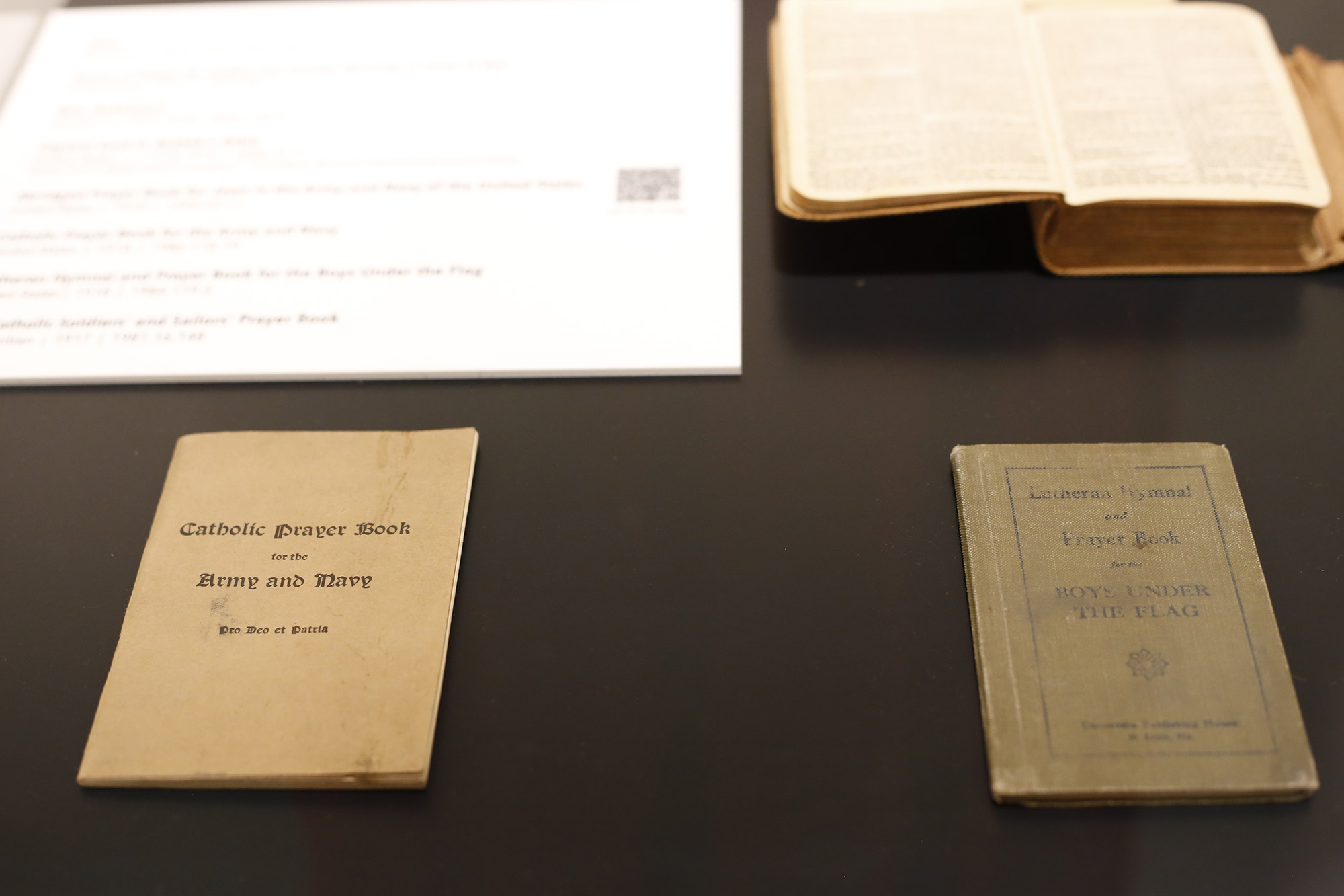 Modern photograph of several thin prayer booklets and a small Bible.