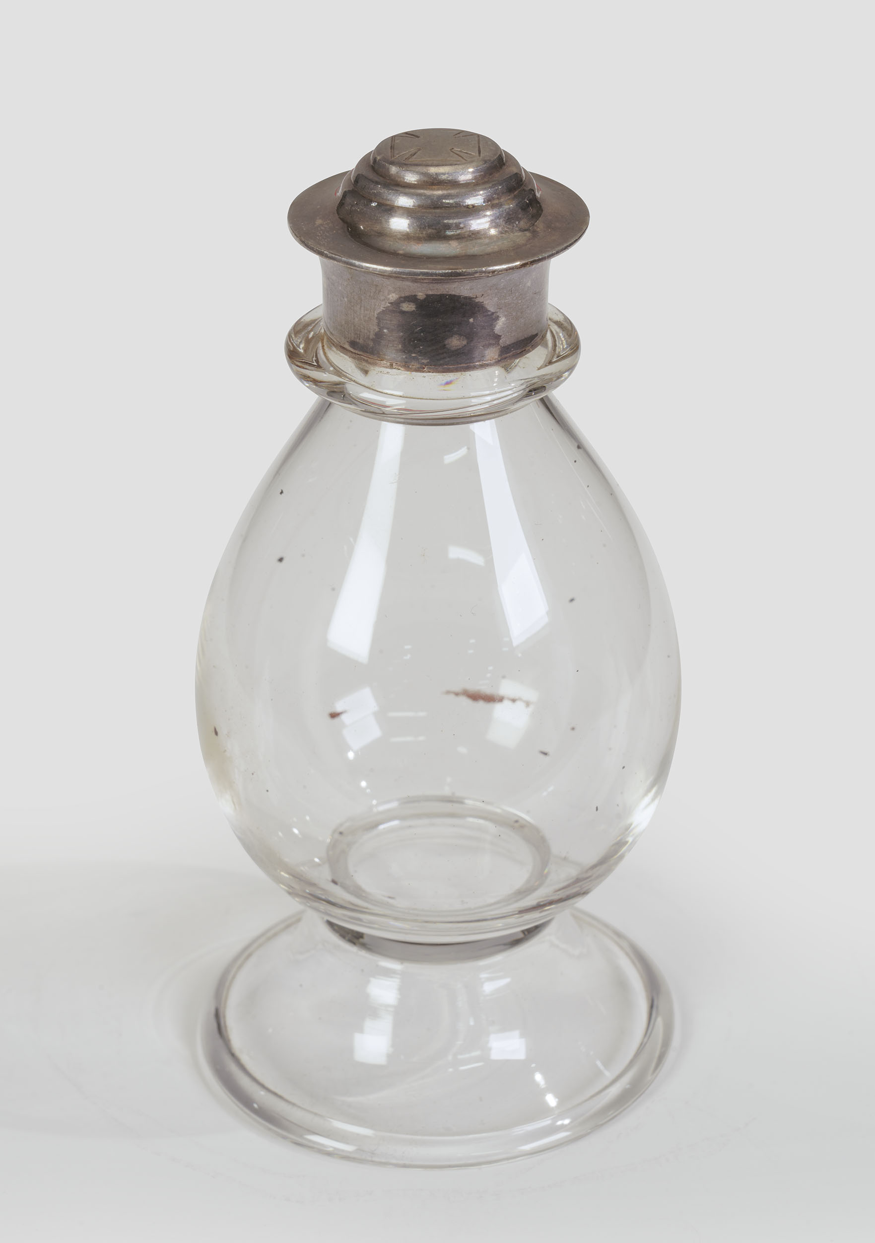 Modern photograph of a bulb-shaped blown glass vessel with a silver cap