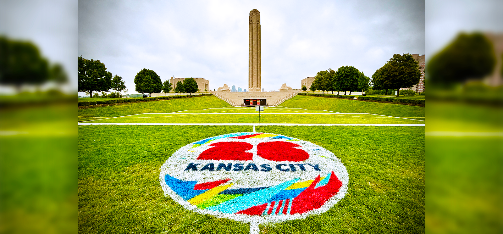 Modern photo of the Liberty Memorial Tower in the background and a painted "26 Kansas City" logo on the grassy terrace in the foreground.