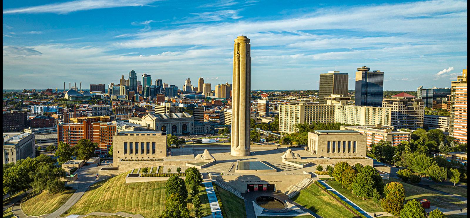 Modern photograph of a soaring aerial view of the Liberty Memorial Tower, Memorial Courtyard, Memory and Exhibit Halls and the Kansas City skyline beyond.